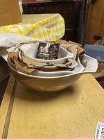 Four nested Pyrex Cinderella mixing bowls in Early American pattern, white interior and brown exterior with vintage inserts inside the bowls.