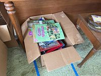 Wide shot of open box filled with various books, top book titled 'Coming to God's World'.