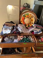 View of scarves, gloves, belts spread on and inside wooden desk drawers
