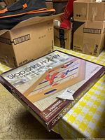 Photo of packaged Slap Shot Hockey tabletop game on a table surrounded by cardboard boxes.