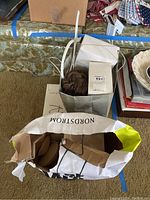 Box containing foam faux breast pads next to Nordstrom and Saks Fifth Avenue shopping bags