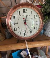 Front view of the antique copper clock showing dial, hands, and numerals