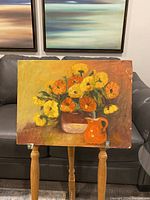 Full view of the oil painting showing flowers in a vase and an orange pitcher on a stand.