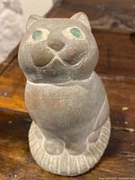 Front view of the cat pottery sculpture showing the face, eyes, and front paws.