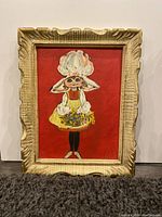 Front view of framed painting showing girl in bonnet holding basket of flowers against red background.