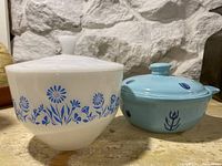 Two ceramic covered bowls, one white with blue floral pattern and one blue with darker blue motifs.