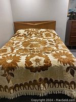 Full view of queen size bed cover with floral pattern and fringe on bed with wooden headboard.