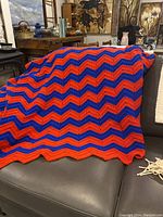 Full view of the retro blanket draped over a sofa showing the chevron pattern and color contrast.