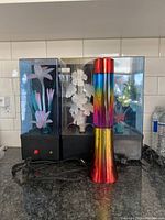 Three retro dancing light boxes with floral designs on a kitchen counter, showing front and side views including a red power switch and power cords.