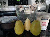 Glass bowls stacked with shells inside, two jar candles and three pear-shaped candles in front, all on kitchen stove top.