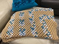 Full view of the folded crochet blanket showing its multi-colored geometric pattern and texture