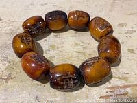 Top view of the vintage hand carved wooden bracelet showing ten barrel-shaped beads each carved with Chinese Buddhist characters.