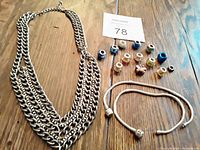 Photo of two Pandora-style silver-tone bracelets lying flat with 13 assorted beads including a butterfly bead and a vintage multi-strand silver-tone chain link necklace on a wooden surface.