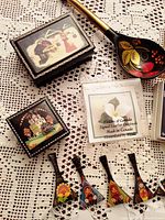 Two Russian handpainted lacquer trinket boxes and a handpainted wooden spoon with floral design, alongside a Canadiana jewelry box labeled Made in Canada.