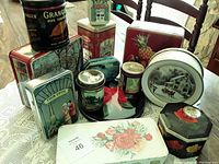 Overview of lot showing multiple vintage tins with biscuit, candy, and tobacco themes on table