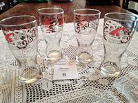 Four mid century modern vintage BBQ beer glasses arranged on crocheted lace tablecloth, showing their height and shape.