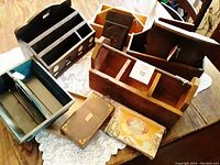 Overview of 10 antique and vintage wooden boxes and one small antique shelf laid out on tabletop for storage and display use.