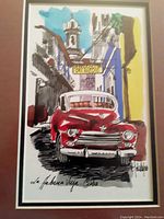 Close-up of one framed print showing a red vintage car and Havana street scene, signed by artist