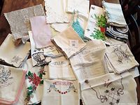 A mix of folded vintage linens showing embroidery, crochet doilies, tablecloths, and runners arranged on a surface.