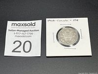 Front side of the 1906 Canadian silver quarter showing the wreath design and denomination 25 Cents inside a cardboard coin holder.