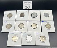 Top view showing an assortment of twelve Canadian 5 cent coins dated between 1942 and 1957 in individual cardboard holders.