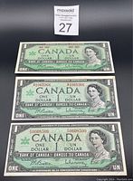 Front sides of three 1967 Canadian $1 bills including error bill