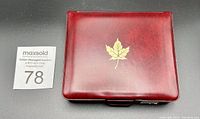 Closed red leather case embossed with gold maple leaf, containing the coin set.