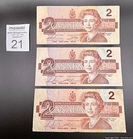 Photo showing front side of three 1986 Canadian $2 paper currency bills, featuring Queen Elizabeth II portrait.