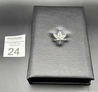Closed black case with silver maple leaf emblem on top, showing presentation box.