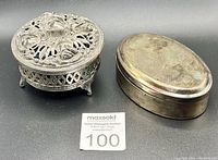 Both trinket boxes closed and displayed side-by-side showing the pewter box's detailed floral lid and the tarnished silver plated box's smooth oval shape.