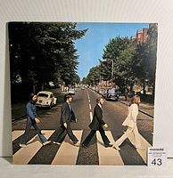Front view of the Abbey Road album cover showing the Beatles walking on a zebra crossing in a street scene.