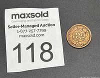 Coin next to maxsold lot number paper for scale and identification