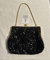 Front view of vintage black beaded handbag showing intricate bead and sequin work with gold-tone chain strap.