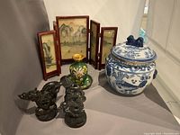 Overview of the lot showing blue and white vase, cloisonné pieces, folding screen, resin dragons, and mat