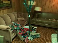 Overall group including couch, partially assembled tree pole with two branches, wreaths on couch, boxes of ornaments and sleeves of tree branches