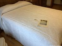 Full view of the beige brocade bedspread covering a queen size bed showing the texture and subtle pattern on the fabric.