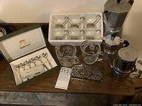 Photo showing all items in the lot: 6 Italian glass espresso cups in white foam tray, 6 silver plated teaspoons in green box, 2 moka coffee makers, 1 Neapolitan coffee maker, glass creamer and sugar bowl, stainless steel napkin holder