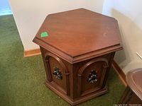 Hexagonal side table showing worn top surface with original hardware on wood front doors.