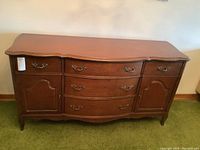 Full front view of the walnut sideboard showing serpentine front, drawers, doors, and original ornate hardware.