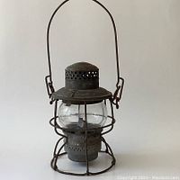 Front view of metal railway lantern with carry handle and clear glass globe