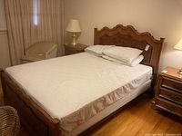 Assembled oak queen bedframe with white comforter and pillows in room setting