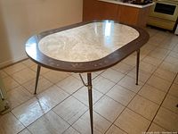 Full view of retro oval kitchen table showing brown border with swirl designs and faux marble center.