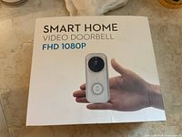 Box front showing the smart home video doorbell product with FHD 1080P label and image of the device held in a hand.
