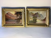 Pair of two framed oil paintings of Scottish Highlands landscapes side by side on a white background showing full front views of frames and artwork.