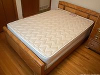 Full view of vintage double bed frame with waterfall style footboard and mattress on top.