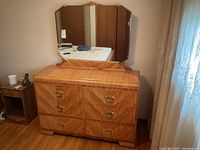 Frontal view of waterfall style dresser with attached tri-panel bevelled mirror