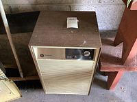 Front and top view of a beige and brown Westinghouse dehumidifier with rotary dial and indicator light.