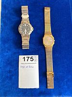 Two men's wristwatches displayed on blue cloth, showing the BVLGARI watch on left and the BULOVA watch on right alongside notes.