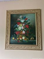 Overall view of framed floral and fruit still life painting on wall