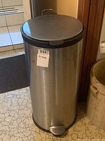 Front view of stainless steel trash bin showing foot pedal and closed lid